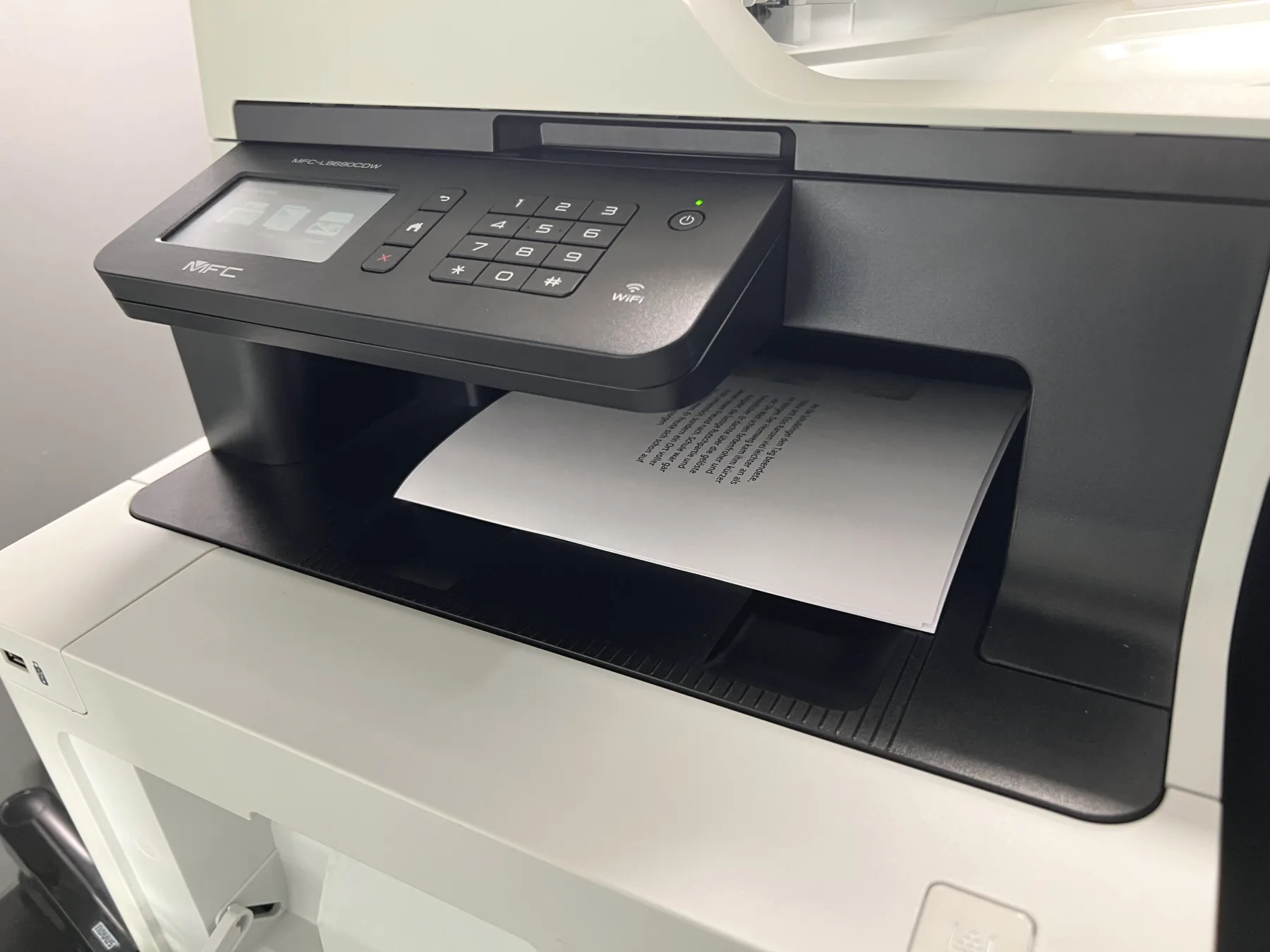 Ein Laserdrucker gibt einen bedruckten Bogen in die Papierablage aus.