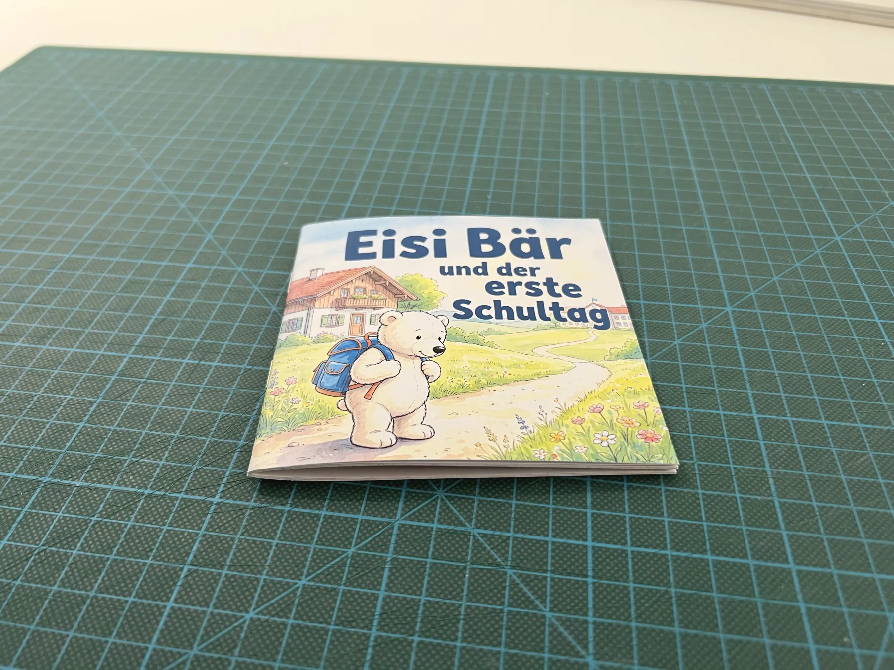 Das fertig geschnittene Büchlein „Eisi Bär und der erste Schultag“ steht aufgeklappt auf einer Schneidematte.